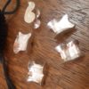 5 replica pewter knucklebones, showing the various ways they can fall. Patial view of a drawstring bag