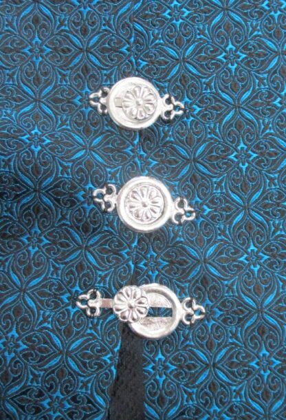 interlocking clasp sewn an a blue and black brocad showing fasteninge