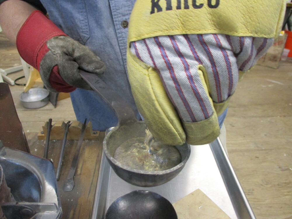 Pouring the still molten metal from the inside of the bell back into the melting ladle.