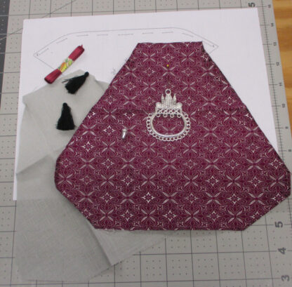 Contents of a kit to make a small purse in purple brocade.
