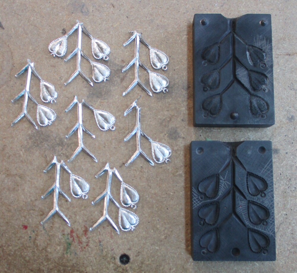 Castings of heart spangle mold with complete hearts cut off and incomplete castings left to compare and correct.