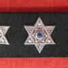 three hexagram studs on a black strap in front of a red ground