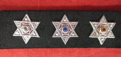 three hexagram studs on a black strap in front of a red ground