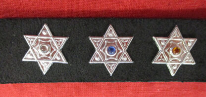 three hexagram studs on a black strap in front of a red ground