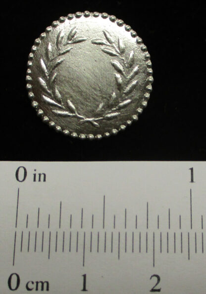 The 3/4" laurel wreath button shown with a scale