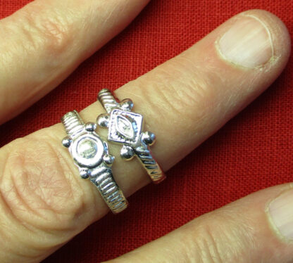 Two similar rings, one with a pretend stone setting, the other with a vulva.