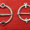 Two similar ring brooches, one with two stones, one with a penis and vulva