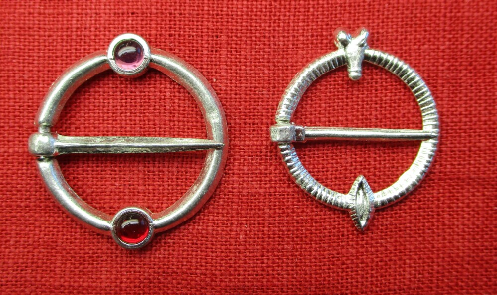 Two similar ring brooches, one with two stones, one with a penis and vulva