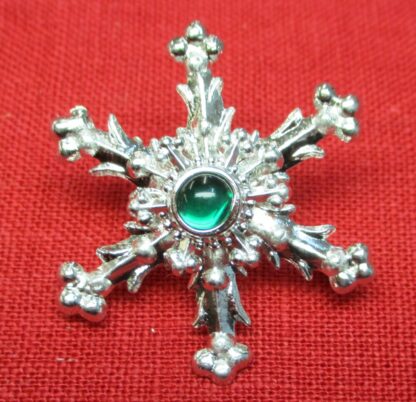 Snowflake brooch with green glass stone