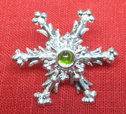 Snowflake brooch with light green glass stone