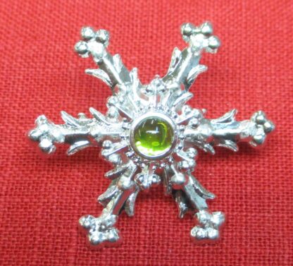 Snowflake brooch with light green glass stone