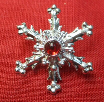 Snowflake brooch with red glass stone
