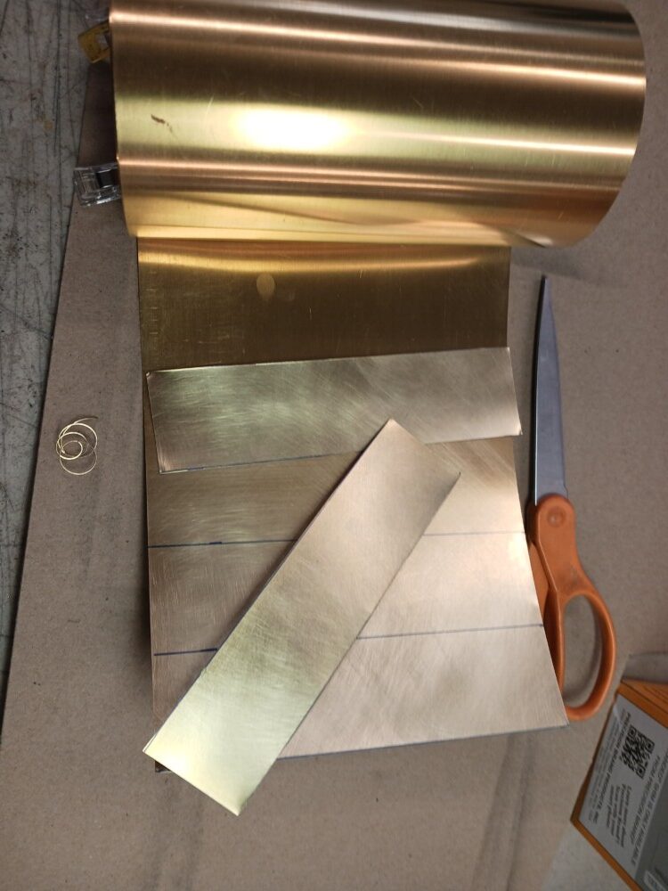 stock polished, lines for strips drawn, with one strip cut off; scissors
